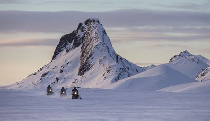 Snowmobiling in Langjökull Glacier in Iceland with cliff behind
